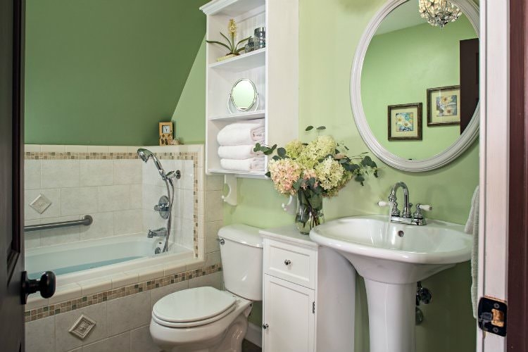 Bright green guest bathroom with a sit down tiled tub and shower, ceramic appliances