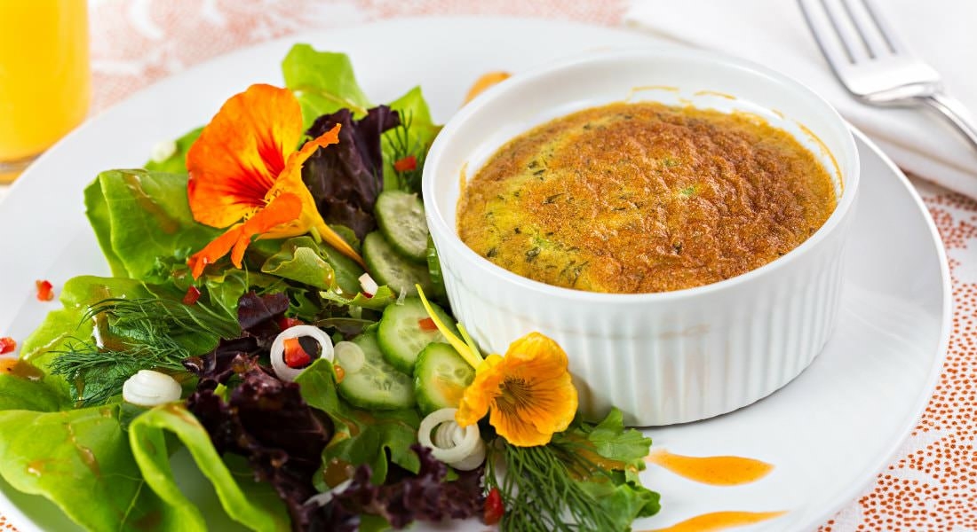 A delicious meal plated on white dishes, a garden salad with a side of French onion soup.
