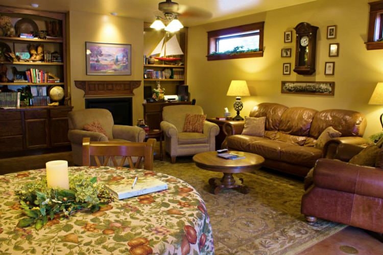 A cream interior sitting room with leather seating options, a large floral area rug and a small round table.