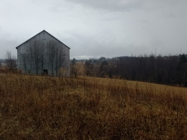 Midwinter barn in barren field with cloudy sky