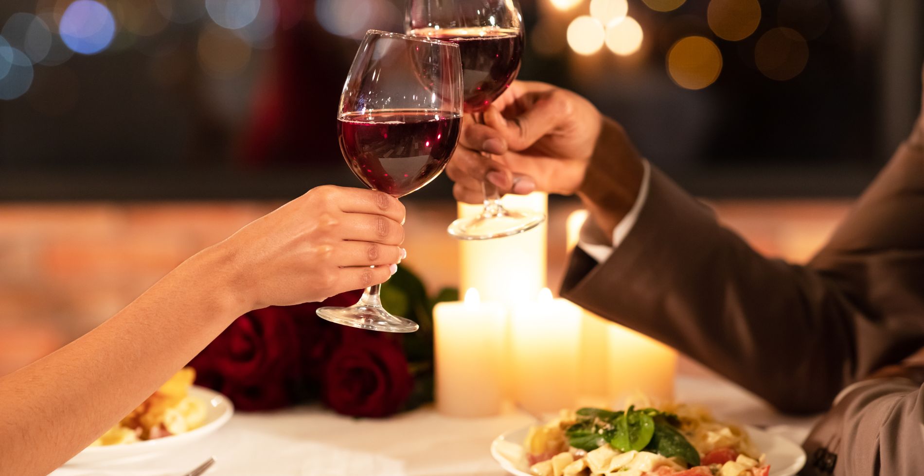 A couple clinking wine glasses while having dinner at a restaurant