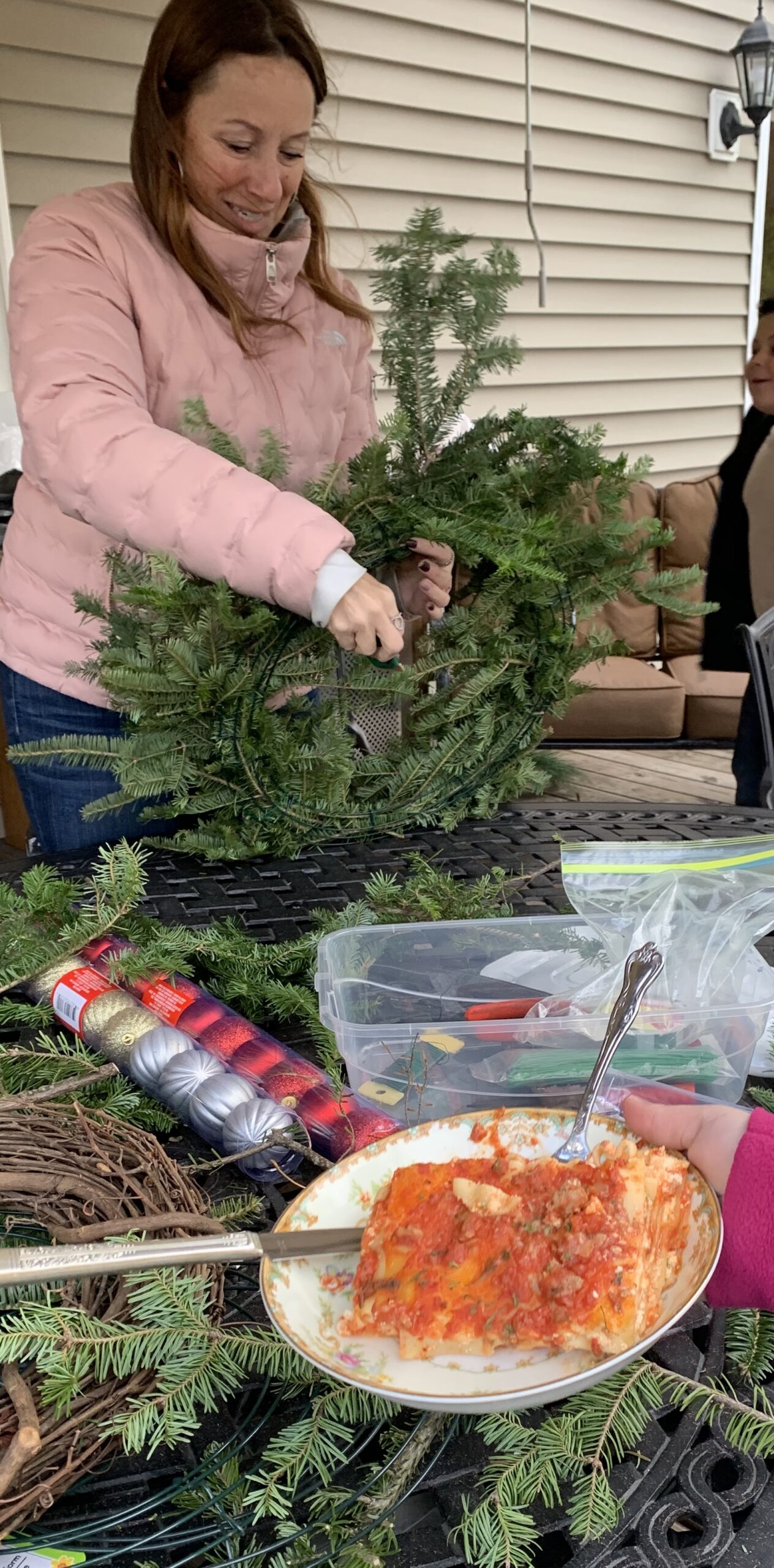 girl holding a wreath with a plate of lasagna