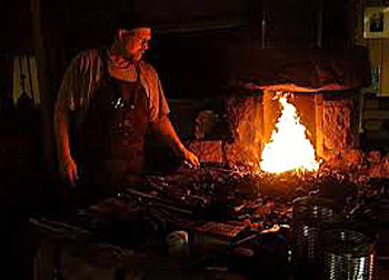 Blacksmith standing at firey forge