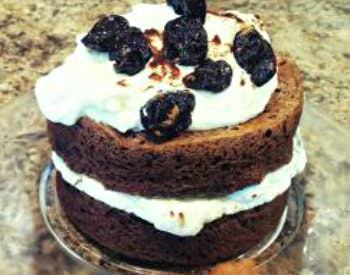 A cake pastry, two layers of brown cake with a thick white icing spread between them.