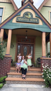 4young girls and one adult sitting on the Hartzell House porch