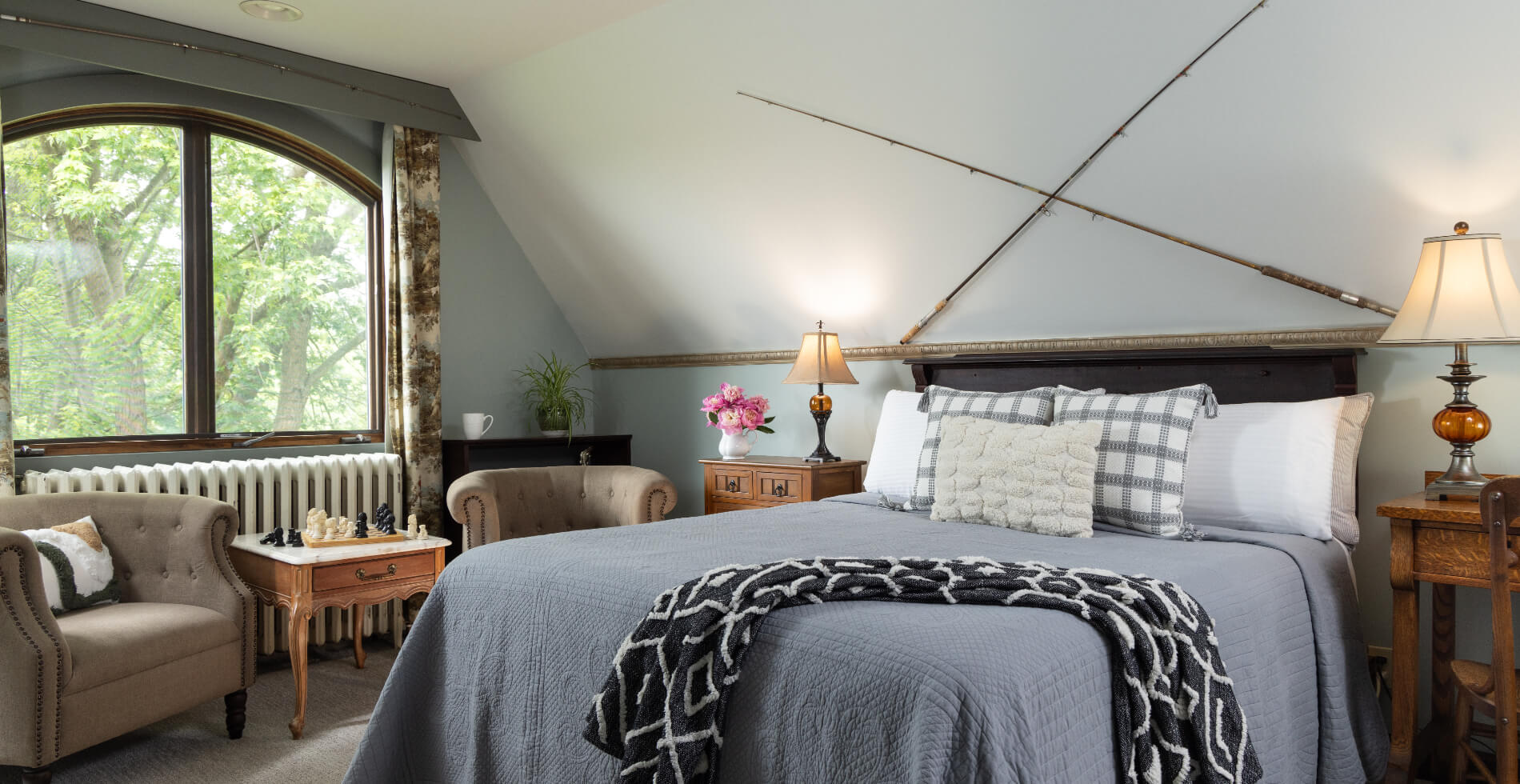 Tan guest bedroom with a shiny pale teal bedding, carpeted flooring, and large wooden vanity