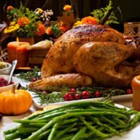 A banquet of traditional Thanksgiving food like turkey, green beans, stuffing, cranberry sauce; food displayed in white dishes