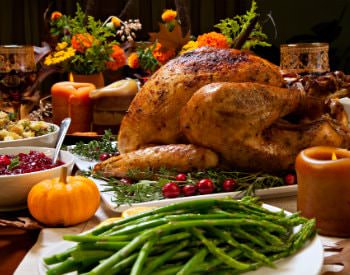 A banquet of traditional Thanksgiving food like turkey, green beans, stuffing, cranberry sauce; food displayed in white dishes