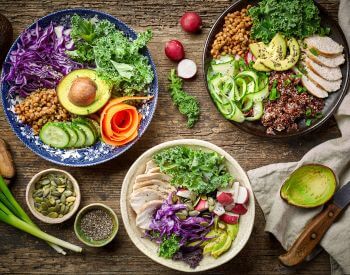 power bowls containing a variety of vegetables and meat sitting on brown wood table