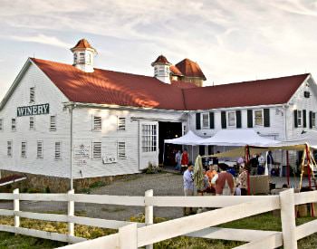 Exterior view of Christian Klay Winery, a white building with red roofing, surrounded by a white picket fence