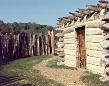 Exterior view of an old wooden lodge from Fort Necessity, surrounded by brown wooden stumps.