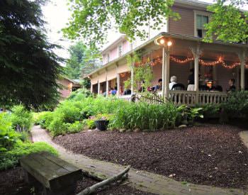 Exterior view of the rivers edge café surrounded by thick green landscaping and twinkle lights on the porch