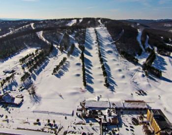 Wide angle view of a ski resort, covered in sparkling white snow and hundreds of pine trees