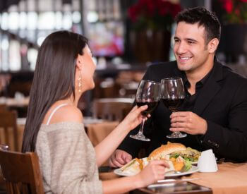 smiling man and woman clinking wine glasses during romantic dinner